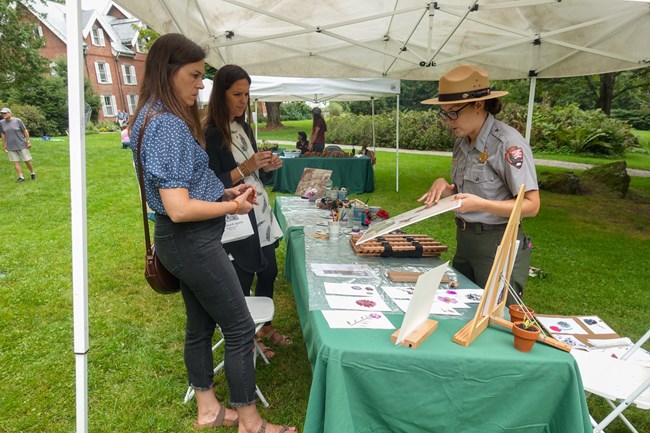A ranger shows two visitors an herbarium print.