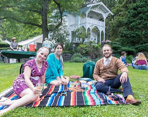 Four people sitting on a colorful blanket picnicking on the Belvedere lawn during Summer Soiree event