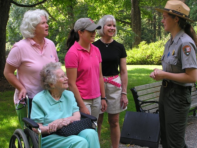Park ranger talks to four people, one of which is an older woman using a wheelchair