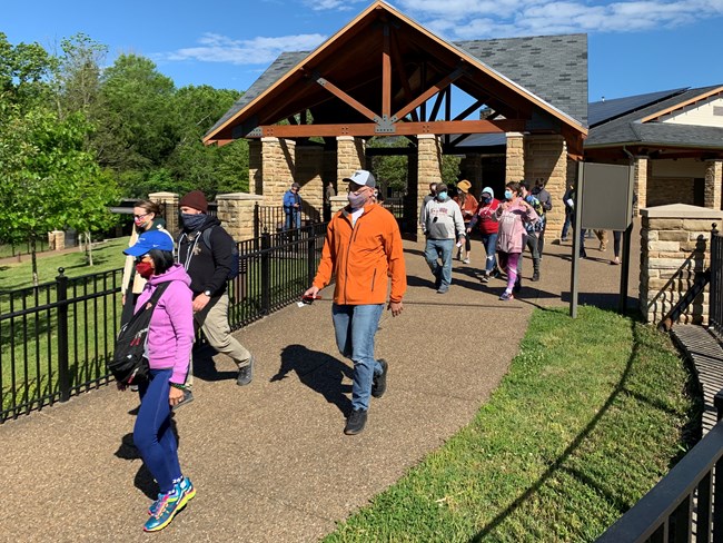 A group of people walk out side of the visitor center