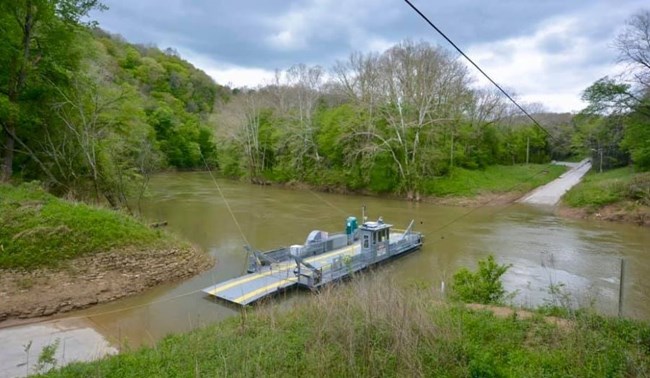 Landscape view of the Green River Ferry floating near a concrete vehicle ramp along the Green River.