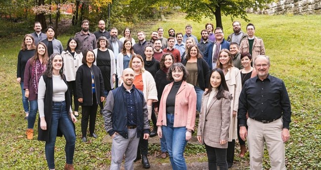A large group of people stand and smile for the camera.
