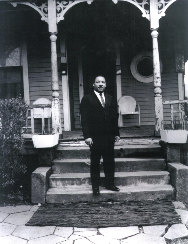 Martin Luther King, Jr. standing at the home he was born in