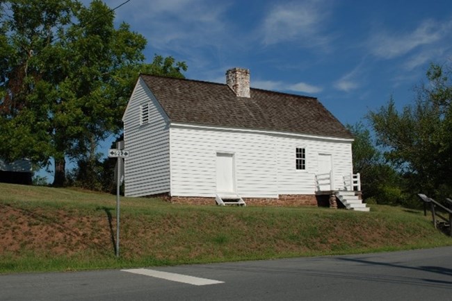 A color photograph of a white painted single story wooden house.
