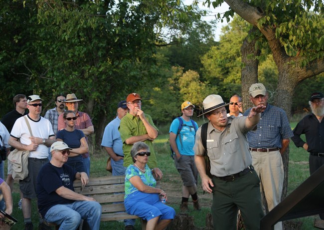 National Park Service Ranger points at the battlefield as he guides visitors on a tour.