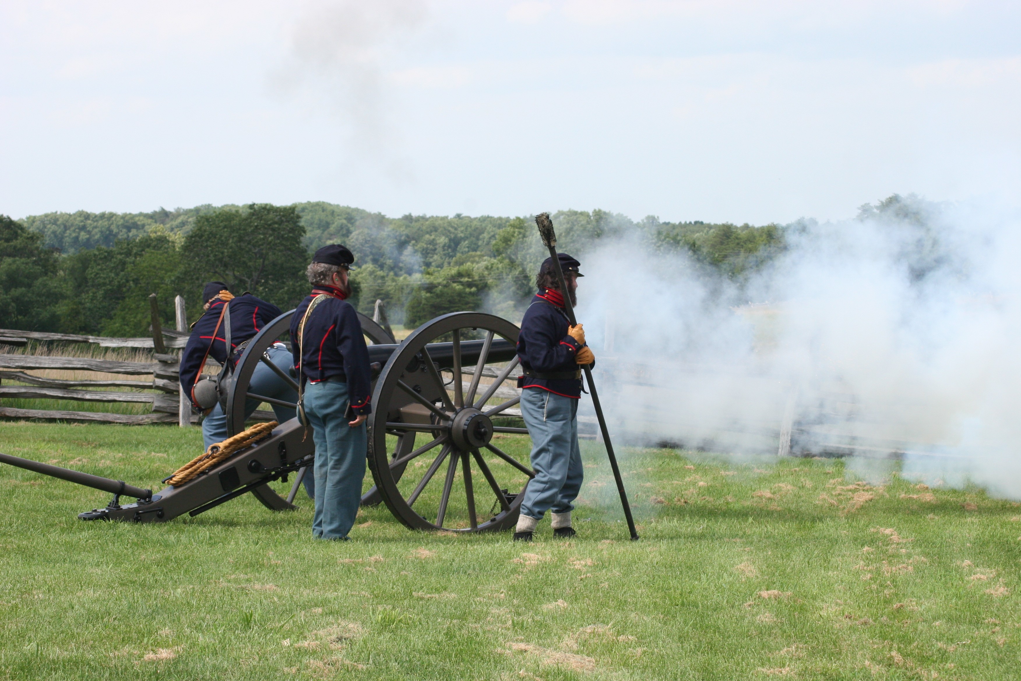 Volunteers in blue Union Civil War uniforms fire a cannon as a demonstration.