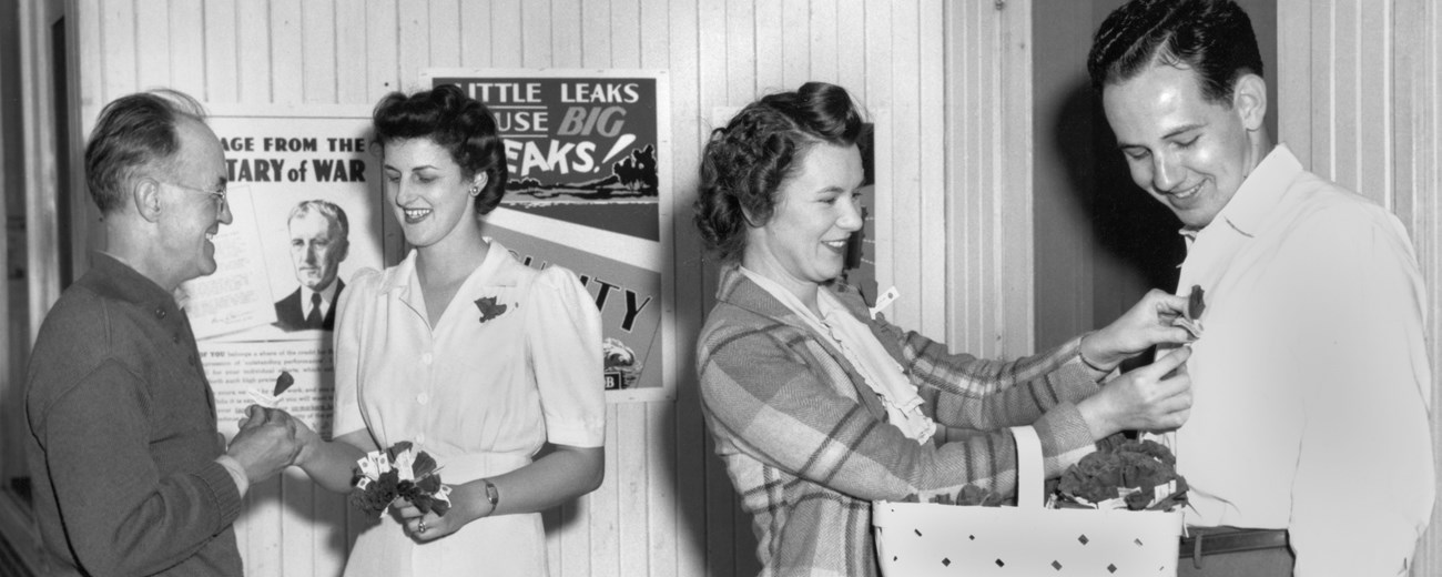 Two women are giving flowers to two men.