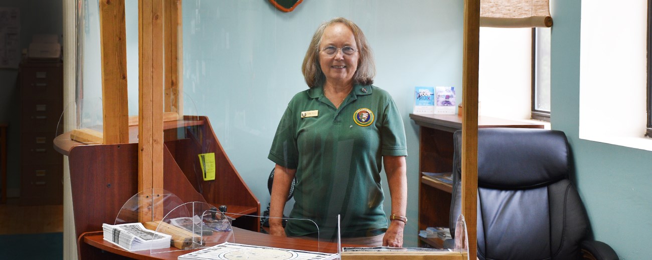 A woman stands behind a desk.