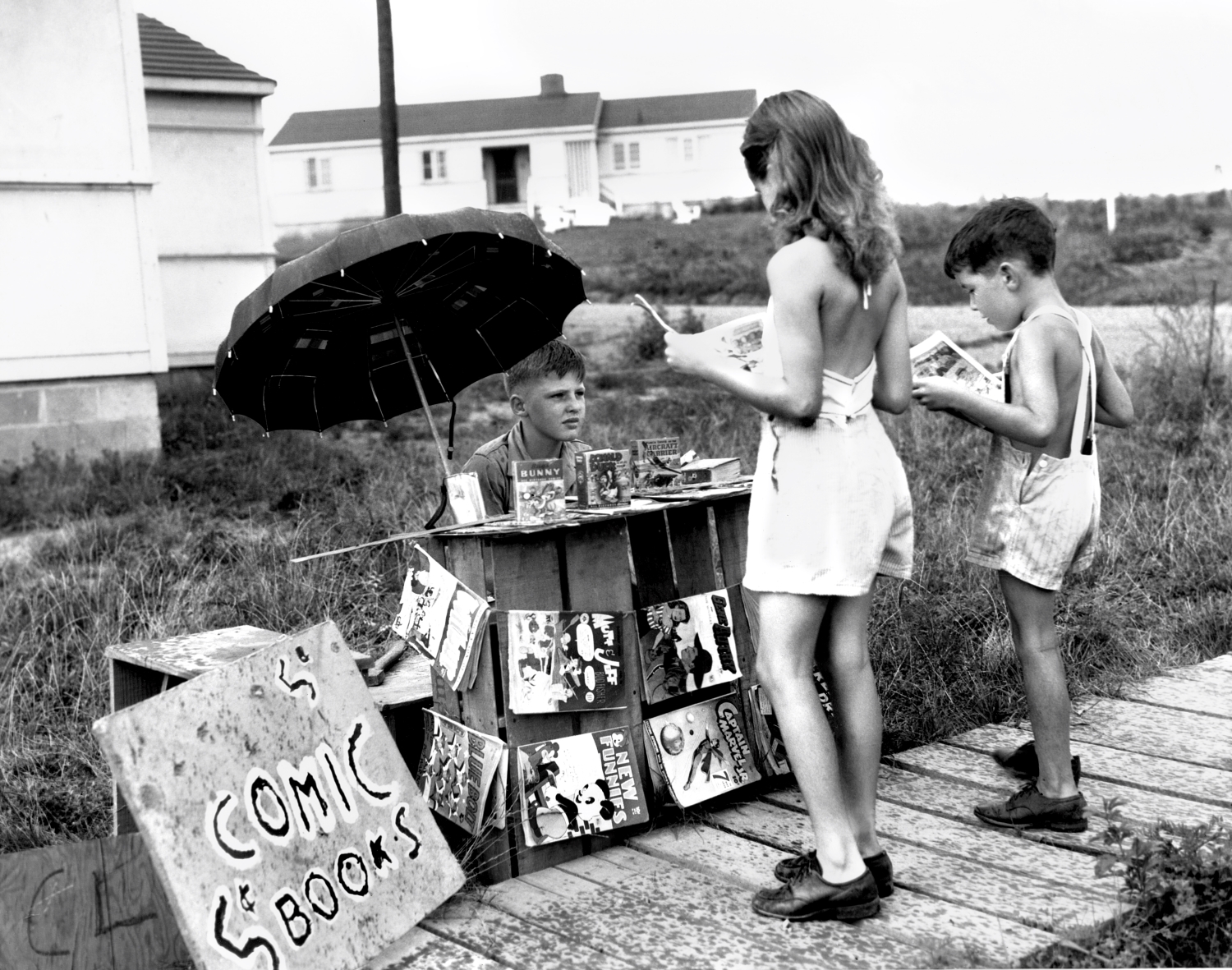 Children read comics at a sidewalk homemade stand