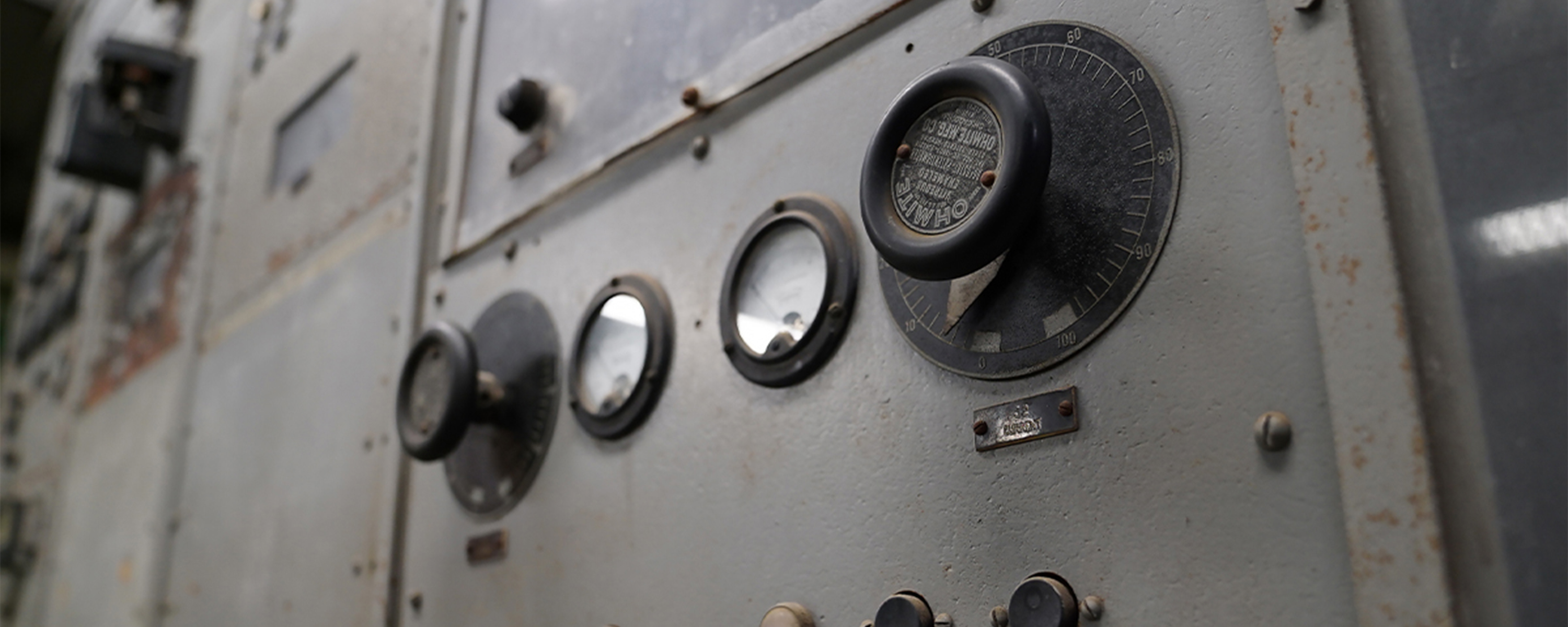 An up-close color photo of several 1940s-era dials and knobs on a metal wall.