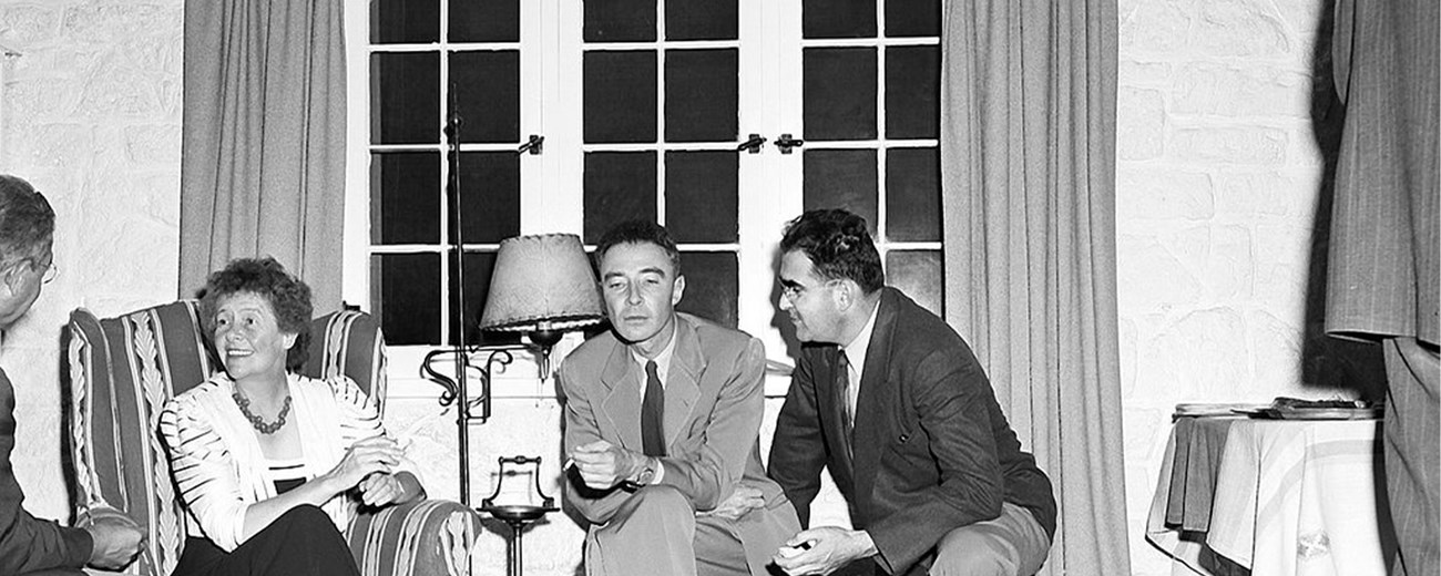 Three men and one woman sit next to each other in a living room.