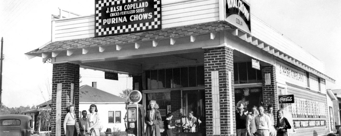 A country store surrounded by people. The store is called “J. Nash Copeland.”