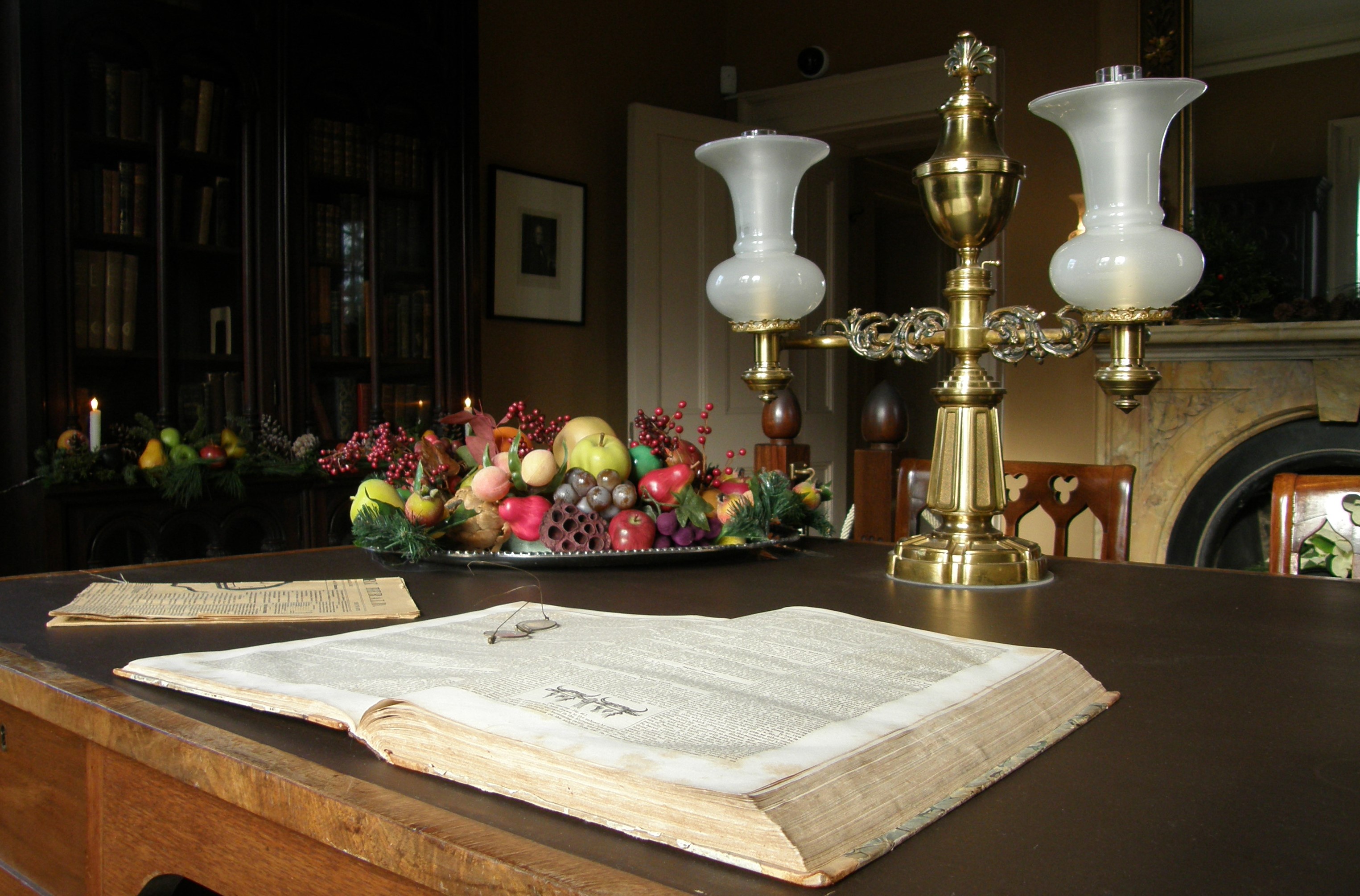 A table decorated with a lamp, a large book, and a bowl of grapes