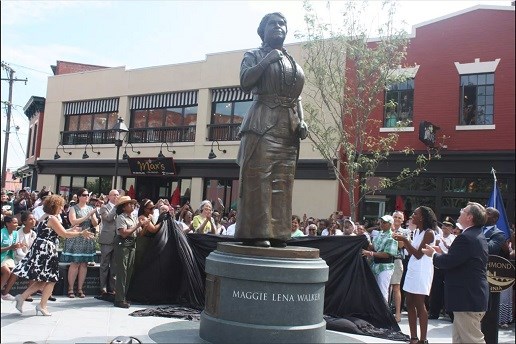 A crowd is gathered outside around the unveiling of a tall, bronze statue of an African American woman