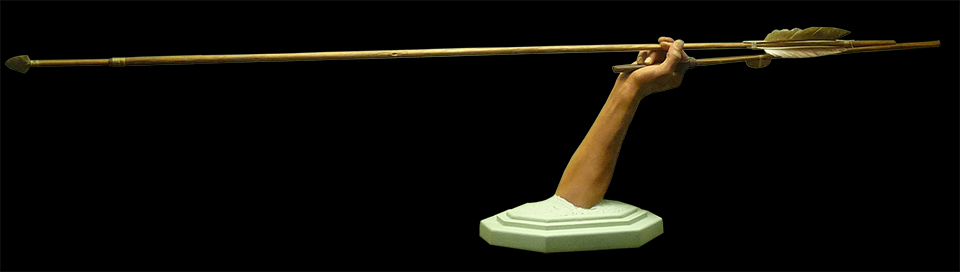 Exhibit displaying a hand holding a wooden spear throwing device.