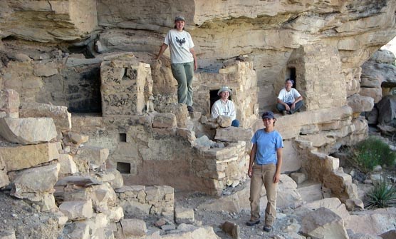 Fort Lewis College intern with archeologists in cliff dwelling.