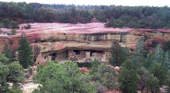 View of Spruce Tree House cliff dwelling with red slurry on mesa top above site.
