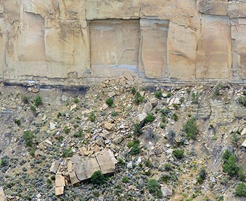 Sandstone cliff face with a square chunk of rock that has fallen away into the canyon below.
