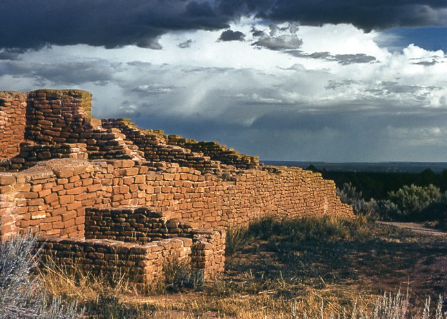 A stormy sky shows rain in the distance and shadows an ancient, hand carved brick wall of unfinished levels