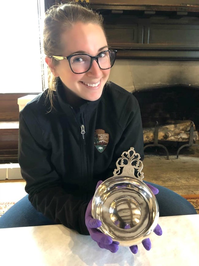 Curator Nikki holds a silver porringer made by Paul Revere