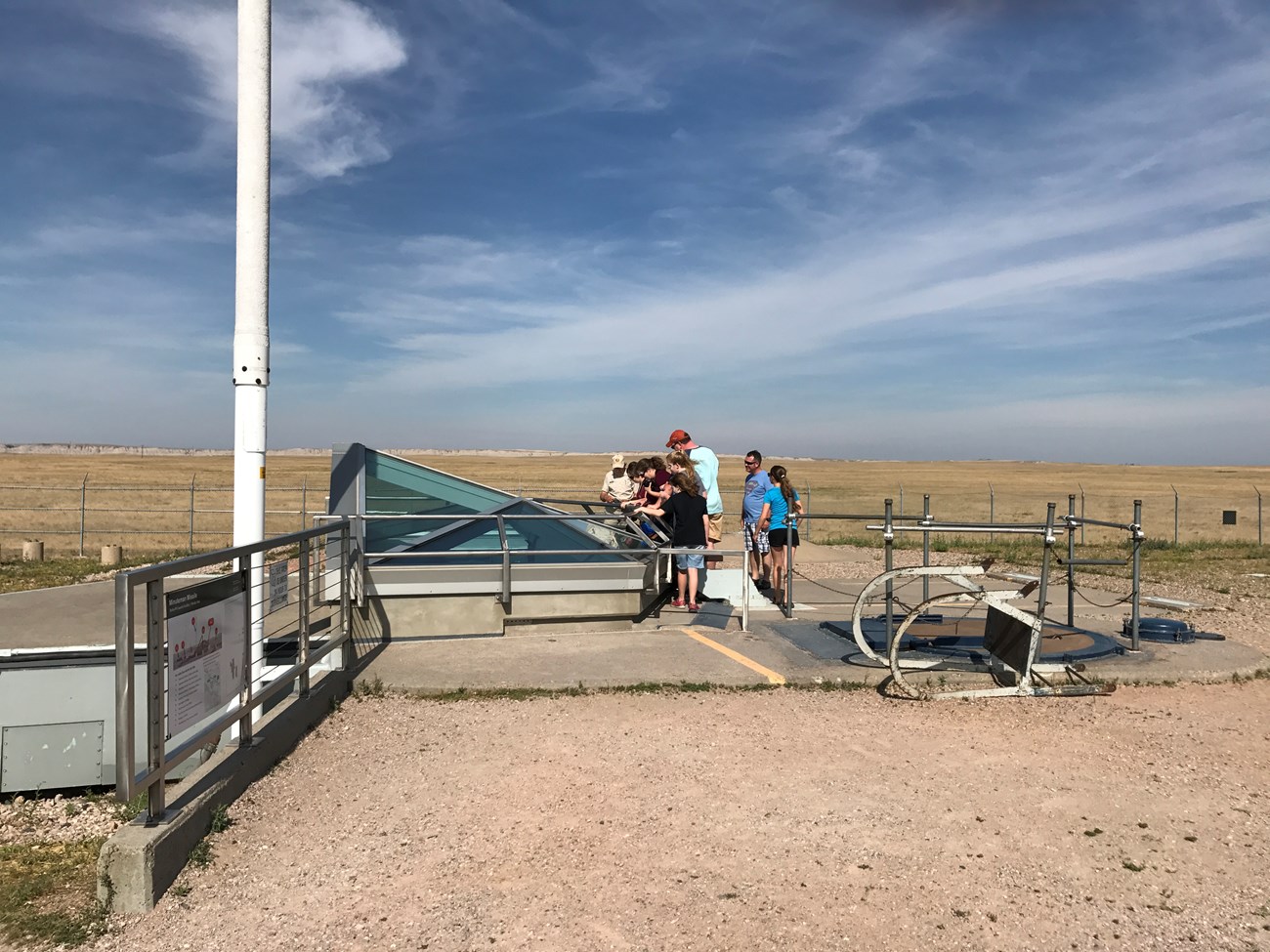 Prairie landscape in the background of people at a glass structure