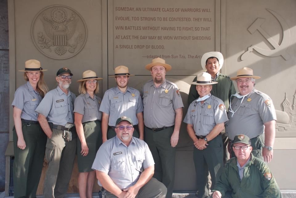 Uniformed staff stand in front of a tall sculpture panel