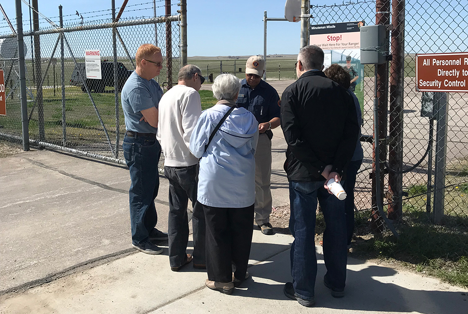 Volunteer greets visitors at a large fenced gate