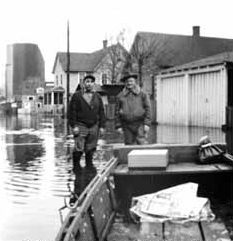Two men standing in the flooded road.