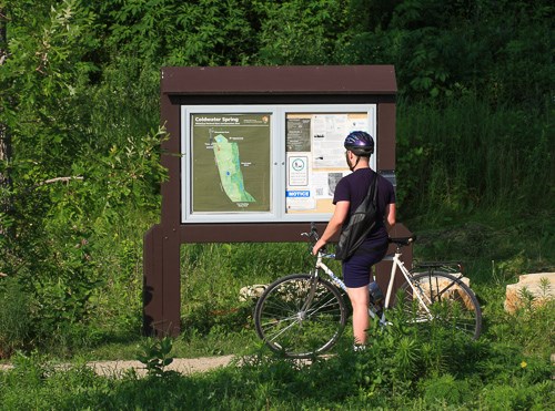 A bicyclist pauses at a map sign.