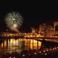 A fireworks display at night in downtown St. Paul reflected in the Mississippi River.