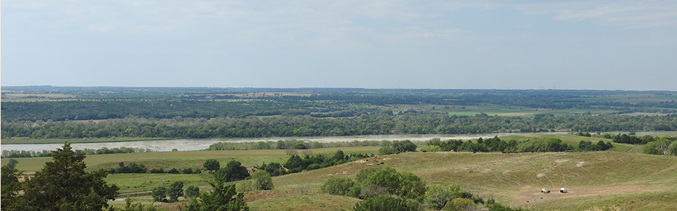 View looking out into a river valley with the Niobrara river and a farmstead in the background.