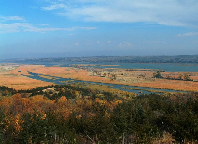 Orange, green, brown, and blue colors make up this autumn picture of the Missouri river from high above an overlook.
