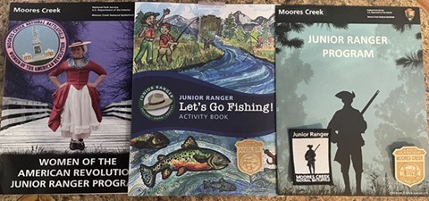 Three Junior Ranger booklets with two badges and two patches on top of them.