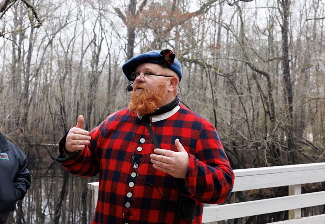 Man in Plaid clothing standing on a wooden bridge