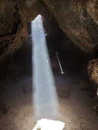 Rays of light shine into the dark lava tube