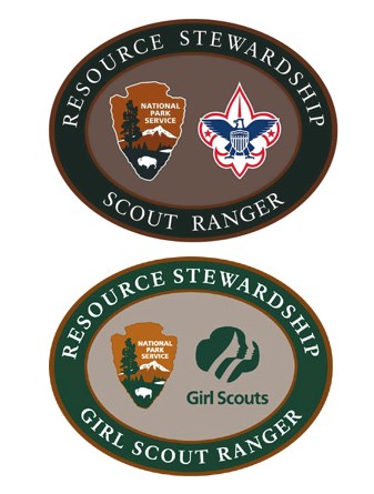 Two oval tan patches with dark green borders. Top patch has NPS arrowhead and Boy Scout logo in center. Bottom has NPS arrowhead and Girl Scout logo in center.