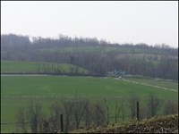 Green farm fields with tree covered hills in background