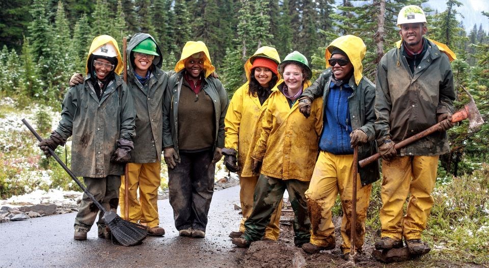 Group of volunteers in rain gear stand on the trail.