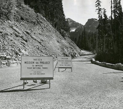 A mountain road with a sign: "This is a Mission 66 project"
