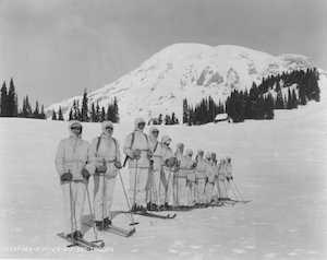 A dozen men in white uniforms on the snow with skis