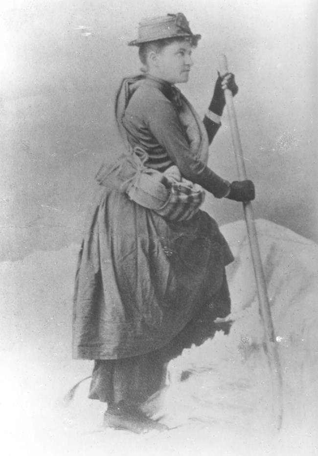 Woman wearing a dress with some climbing gear.