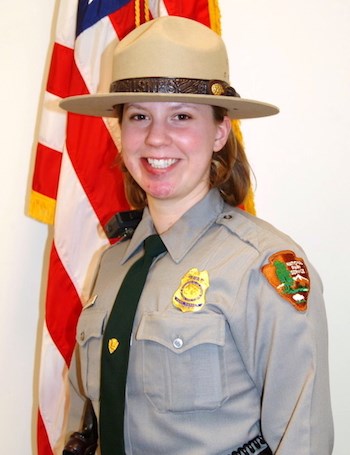 A woman in NPS law enforcement uniform in front of a US flag.
