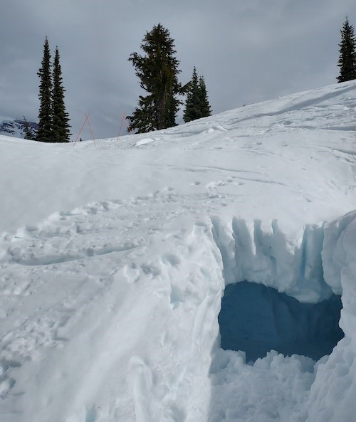 The entrance to a snow cave carved into the side of a snowy slope.