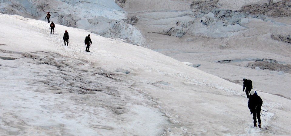 A string of climbers cross a glacier.