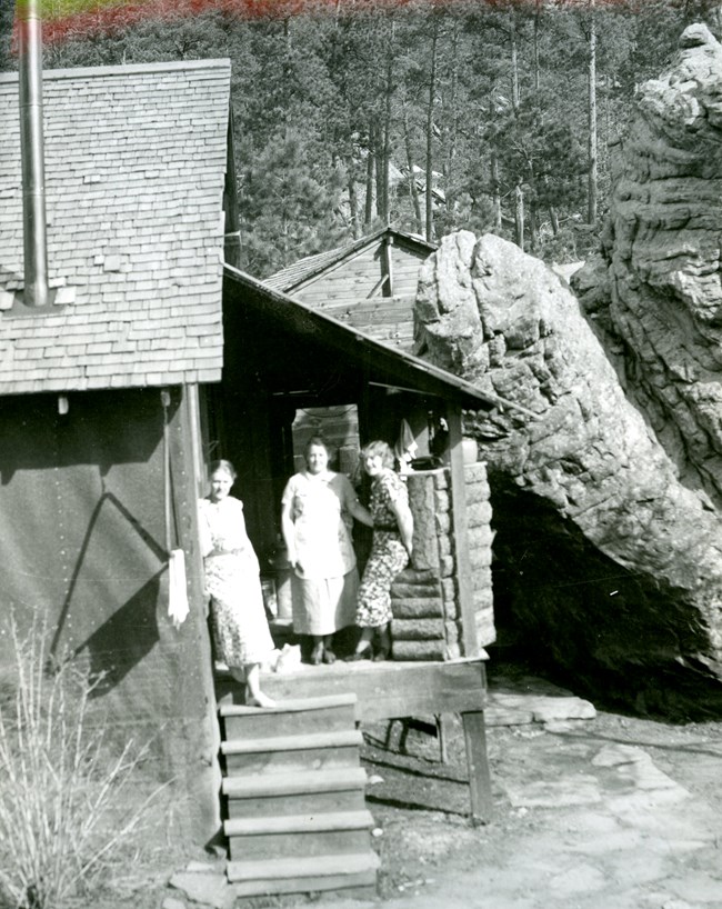 A black and white photo of three women posing outside of the boarding house and restaurant.