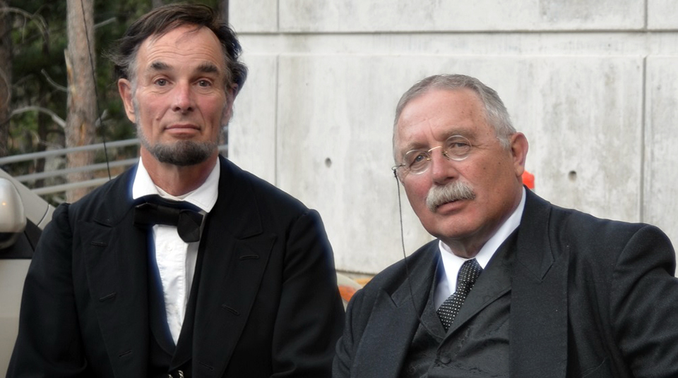Abraham Lincoln reenactor Fritz Klein (left) seated next to Theodore Roosevelt reenactor Gib Young (right) at Mount Rushmore.