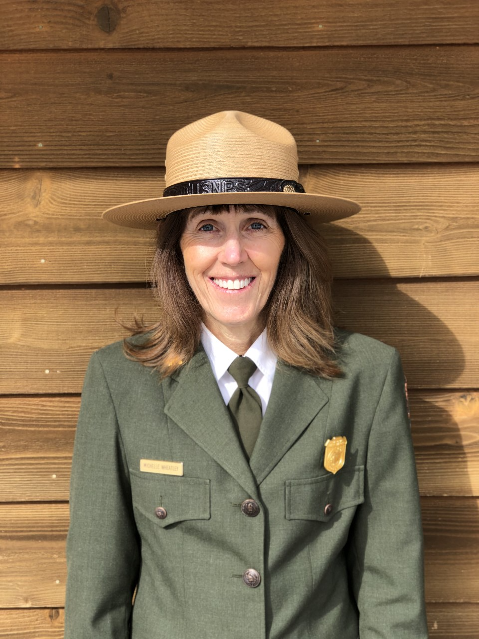 Photo of Michelle Wheatley in a National Park Service uniform with tan ranger hat and green jacket.