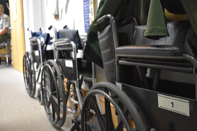 Three black wheelchairs lined up in a hallway inside the Information Center.
