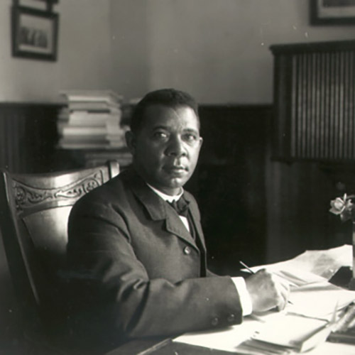 Booker T. Washington sitting at his desk writing
