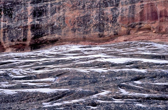 blue-gray sandstone with crossbedding, or hash scores, outlined with melting snow and red sandstone in the background